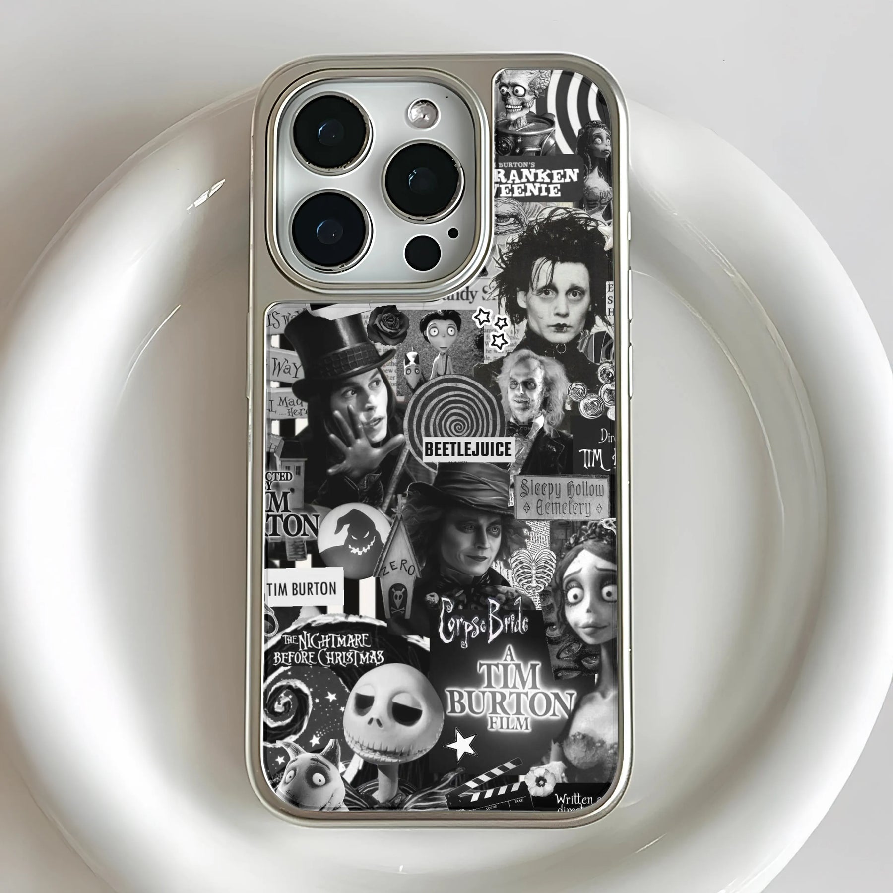 Silver iPhone case with black-and-white Tim Burton collage, rear close-up product view