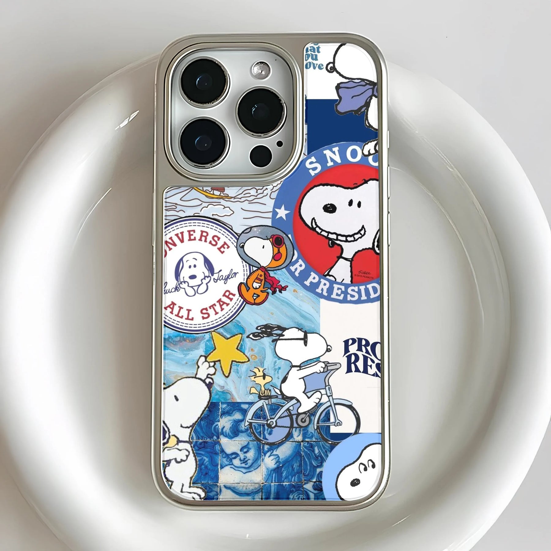 Silver iPhone case with colorful Snoopy collage design, rear close-up camera angle